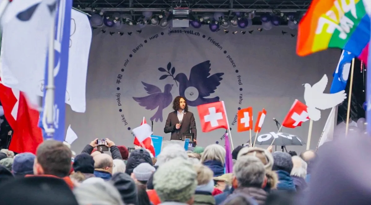 Rede auf der Bühne vor Fahnenmeer